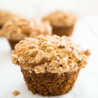 A banana muffin with streusel topping with more muffins in the background.