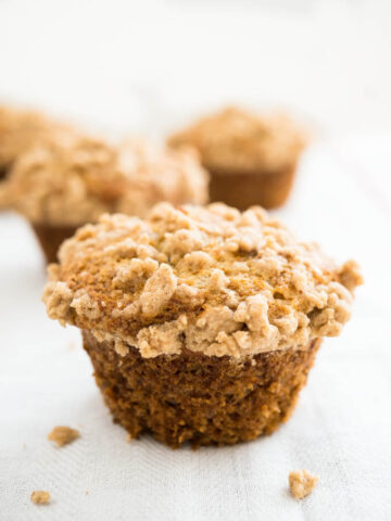 A banana muffin with streusel topping with more muffins in the background.