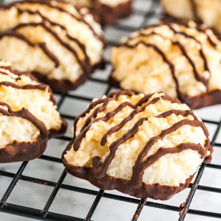Coconut macaroons with chocolate bottoms and stripes on a black cooling rack.