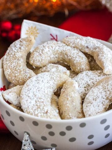 A white bowl with silver dots and a napkin, of Vanillekipferl cookies