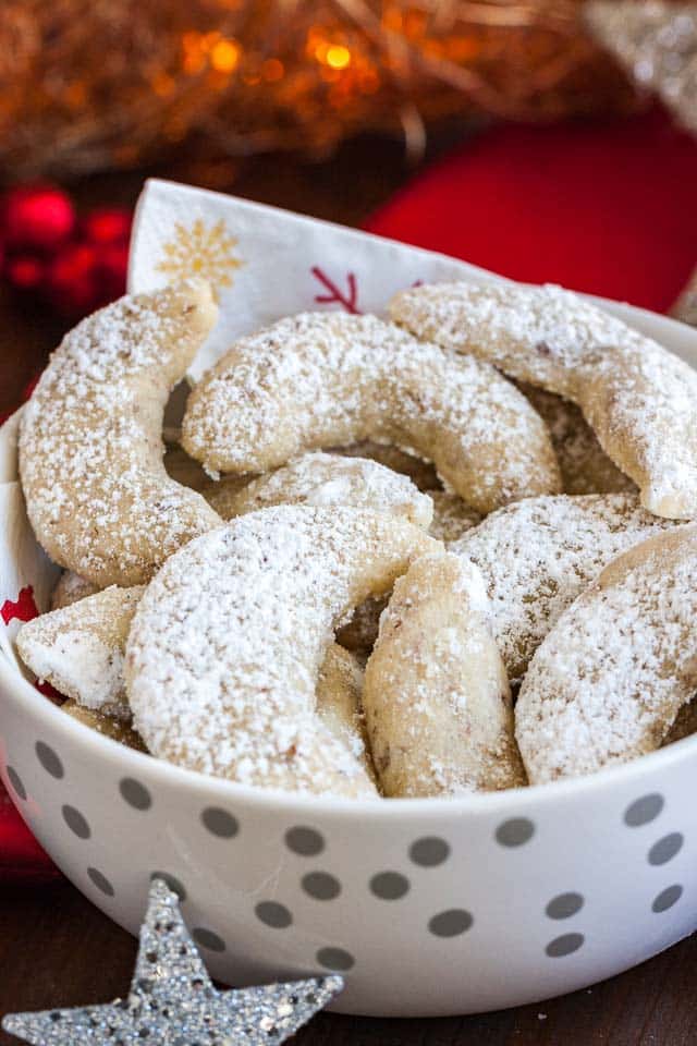 A white bowl with silver dots and a napkin, of Vanillekipferl cookies