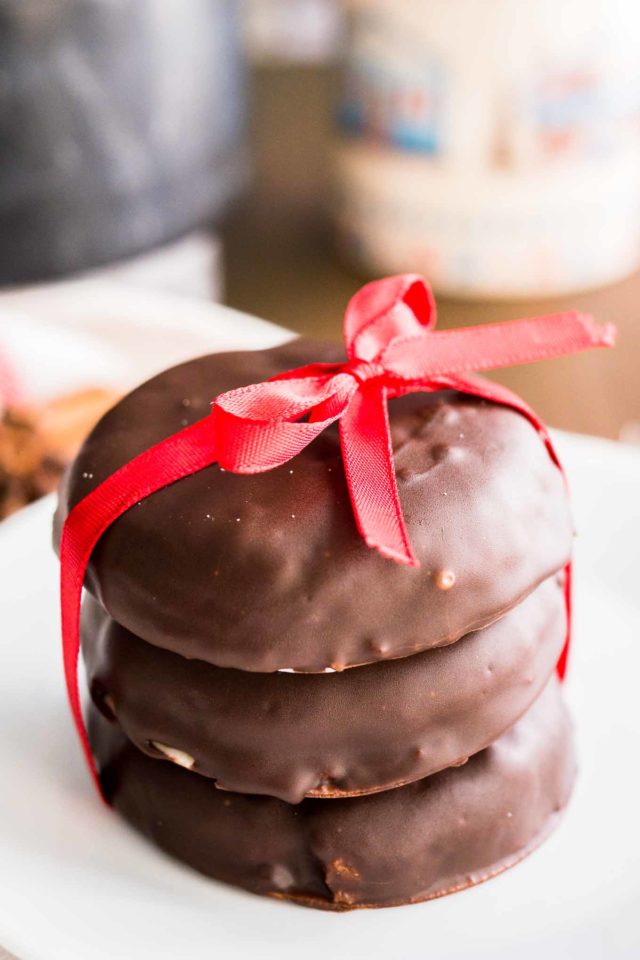 a stack of three chocolate-covered lebkuchen with a red bow on a white plate