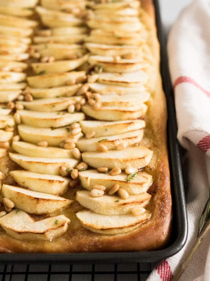 This Apple Cake Recipe is perfect for fall! Yeast dough is brushed with cinnamon butter, topped with fresh apple slices and glazed with honey and pine nuts.