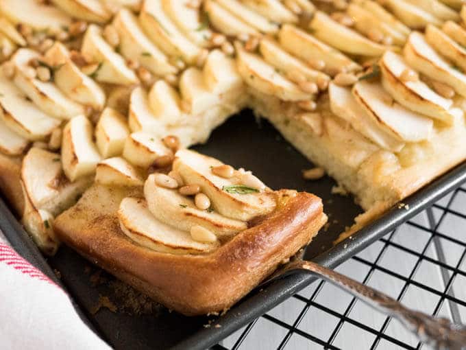 This Apple Cake Recipe is perfect for fall! Yeast dough is brushed with cinnamon butter, topped with fresh apple slices and glazed with honey and pine nuts.