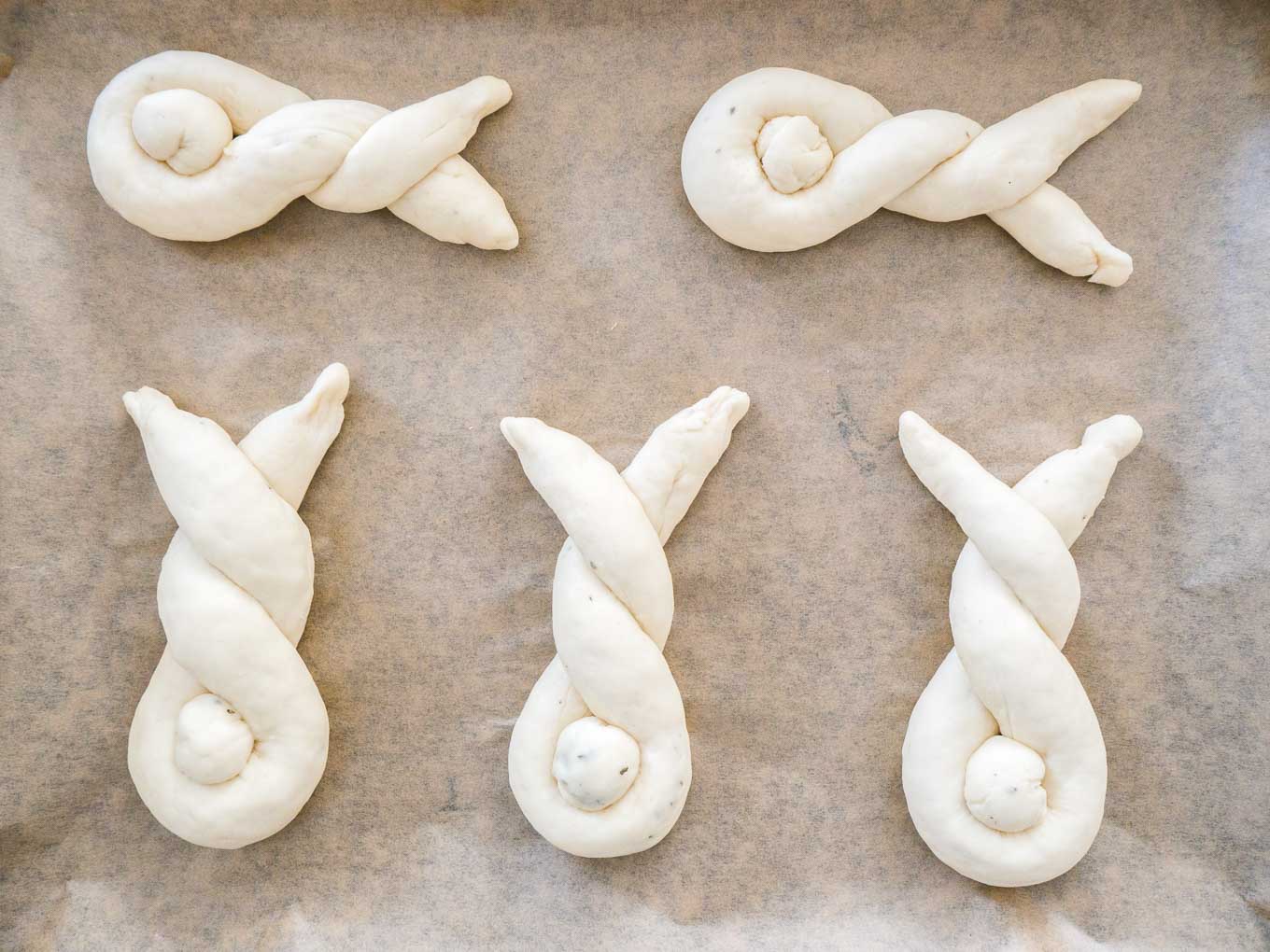 Several bunnies made from dough on brown parchment paper.