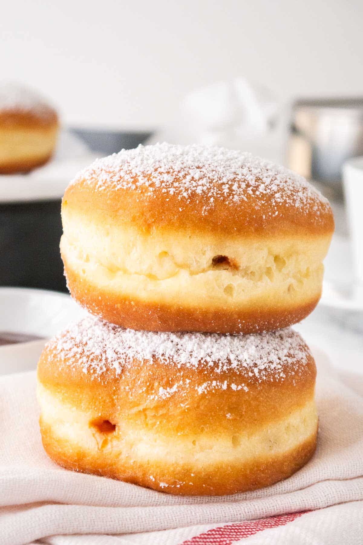 Two Krapfen stacked on a kitchen towel.