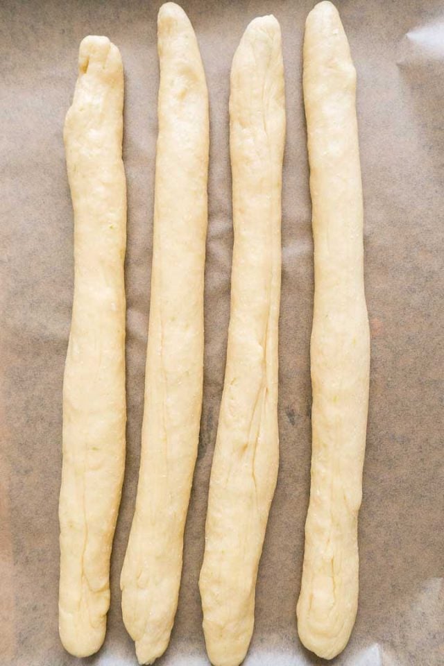 Four strands of dough on parchment.