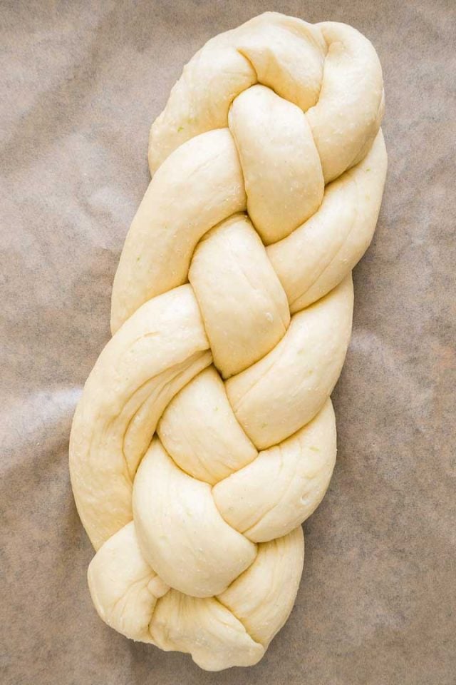 A braided easter bread loaf before baking on parchment paper.