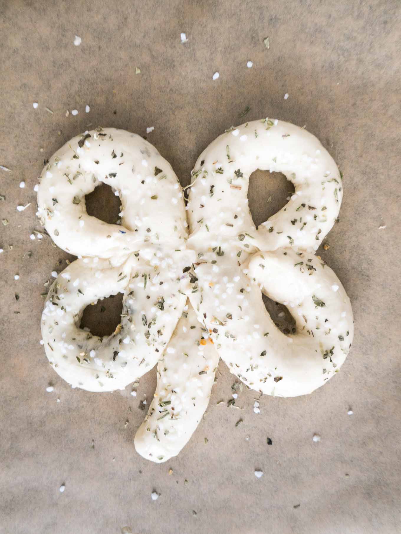 Dough shaped like a shamrock on brown parchment paper.