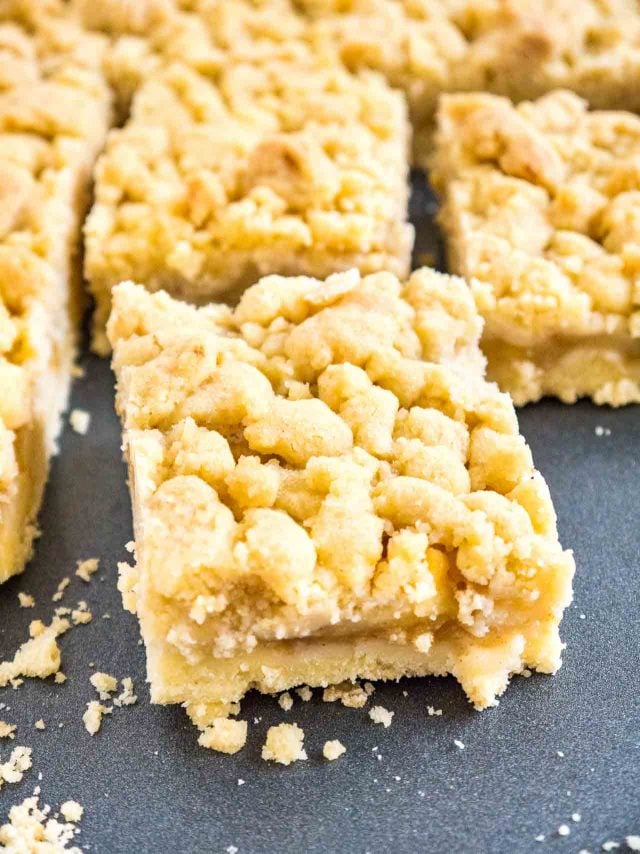 pieces of apple streusel cake on a dark grey baking sheet