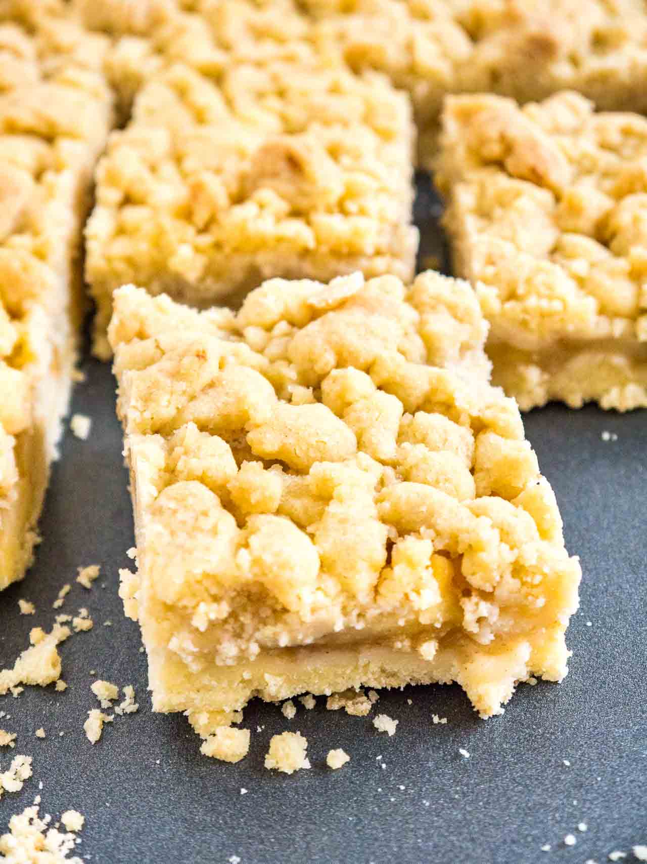 pieces of apple streusel cake on a dark grey baking sheet