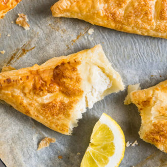 Lemon puff pastry pockets on white parchment with a wedge of lime.