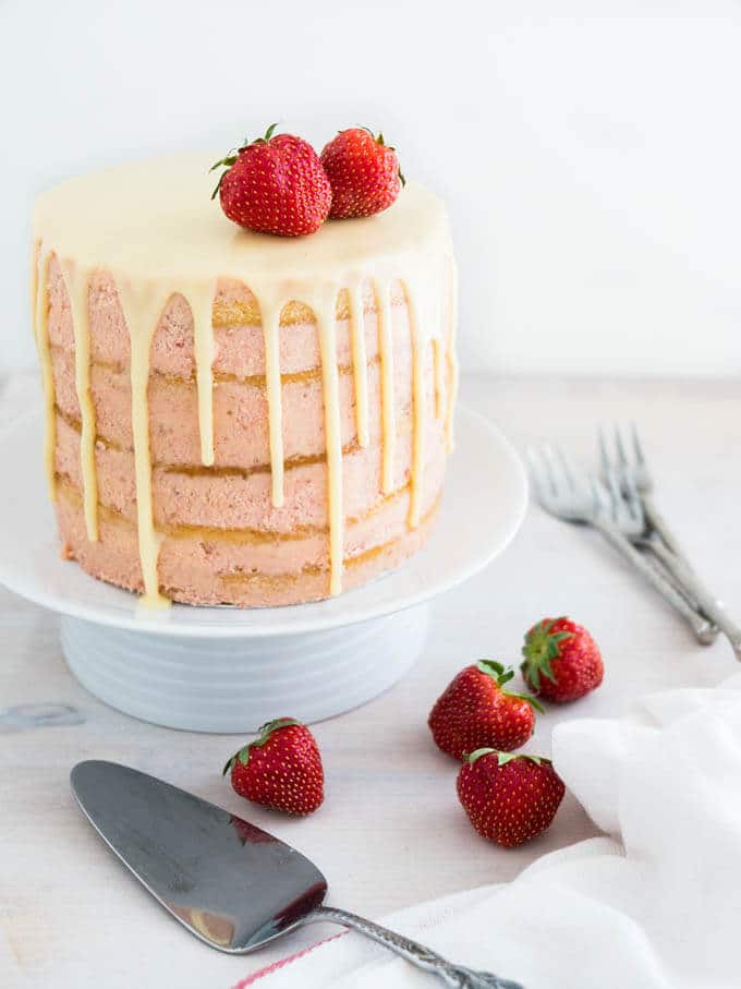 Naked Strawberry Layer Cake is made with fresh Strawberry Meringue Buttercream and fluffy vanilla cake layers. Finished with a white chocolate ganache drip around the edges, this cake is a great centerpiece for every special occasion!