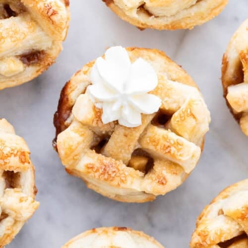 Mini apple pies decorated with whipped cream.
