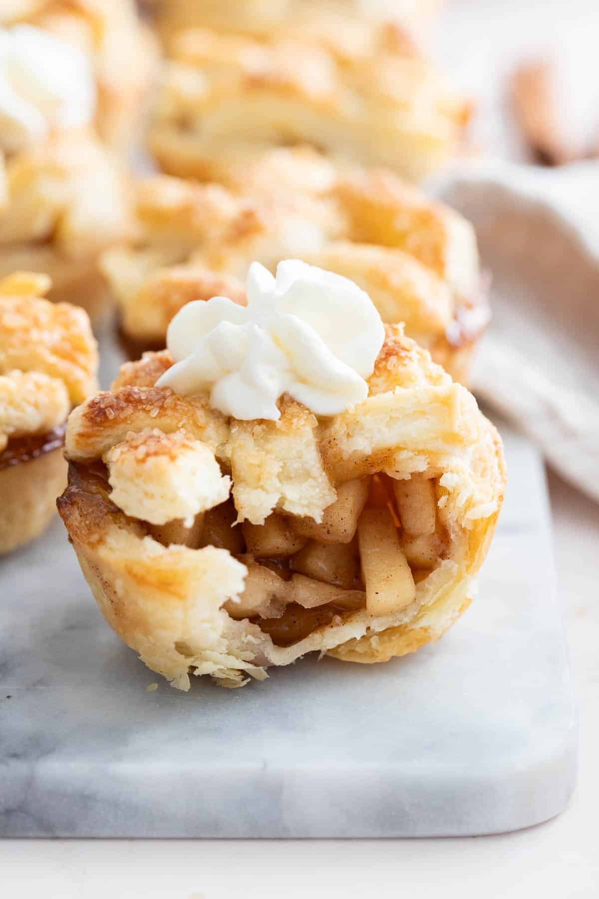 A mini apple pie with a bite taken out of it on a marble board.