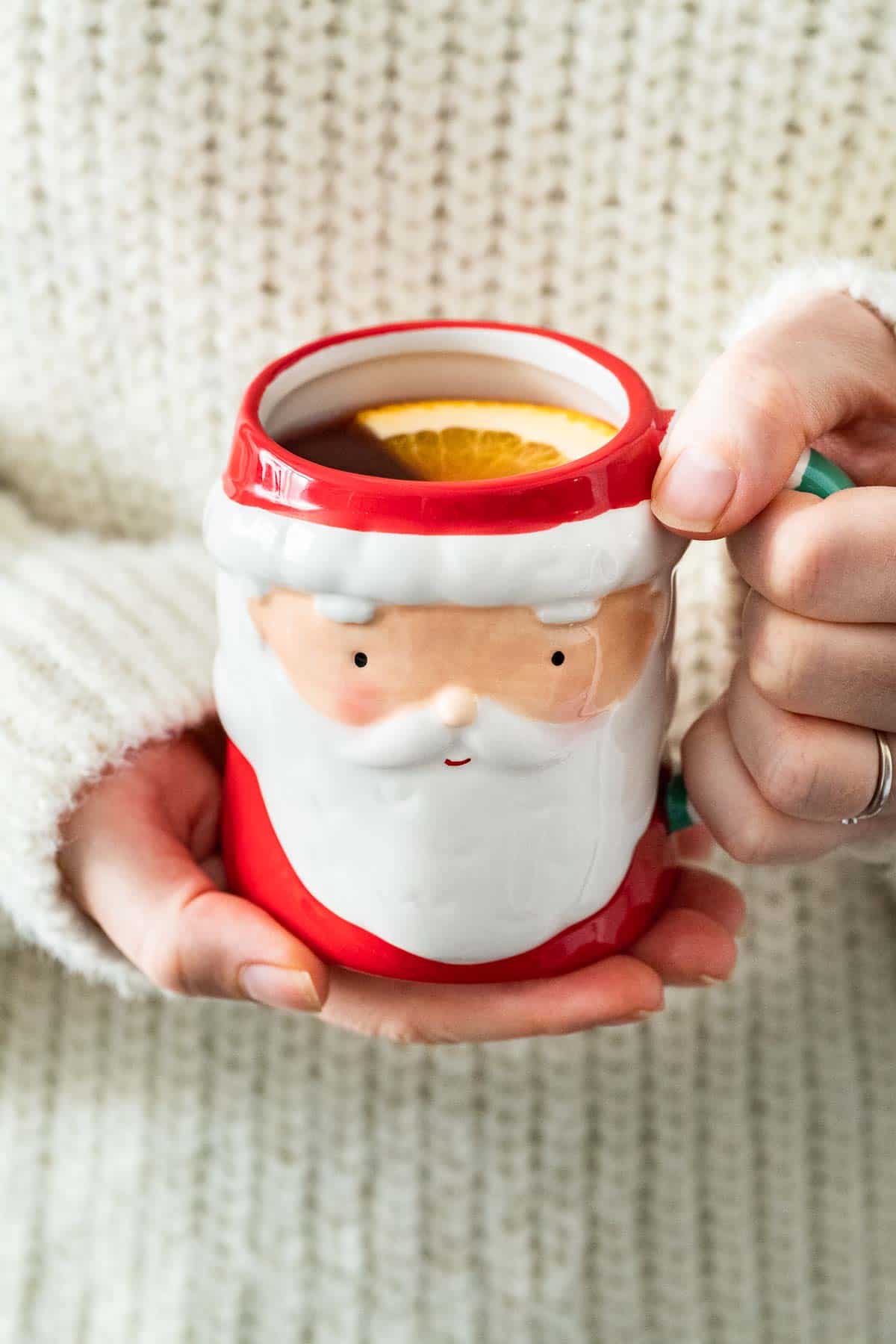 Two hands holding a Santa-shaped mug filled with Kinderpunsch.