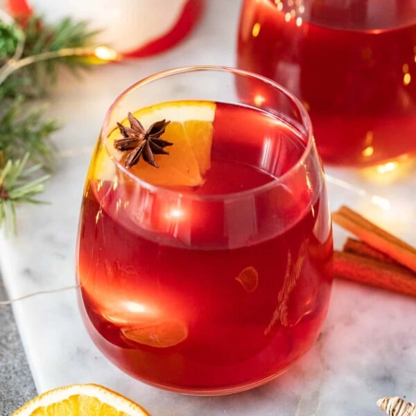 Two glass mugs filled with Kinderpunsch garnished with orange slices and star anise.