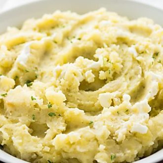 A white bowl with mashed potatoes, garnished with parsley.