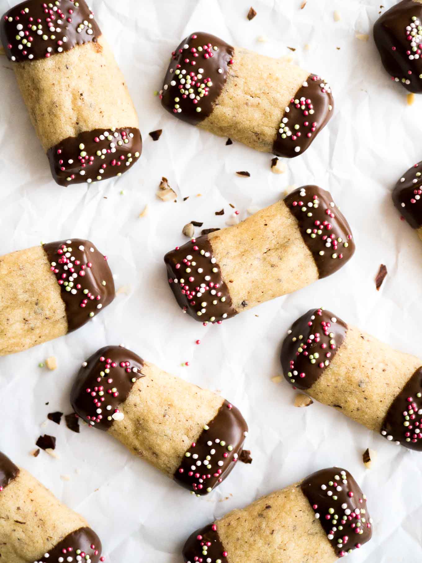 Cookies shaped liked logs with the ends dipped in chocolate on parchment paper.