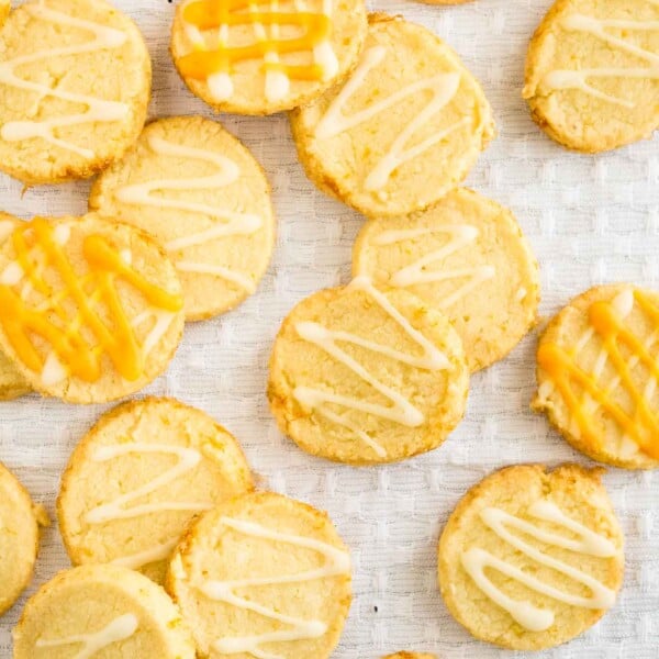 Top-down shot of orange almond cookies on a white tablecloth.