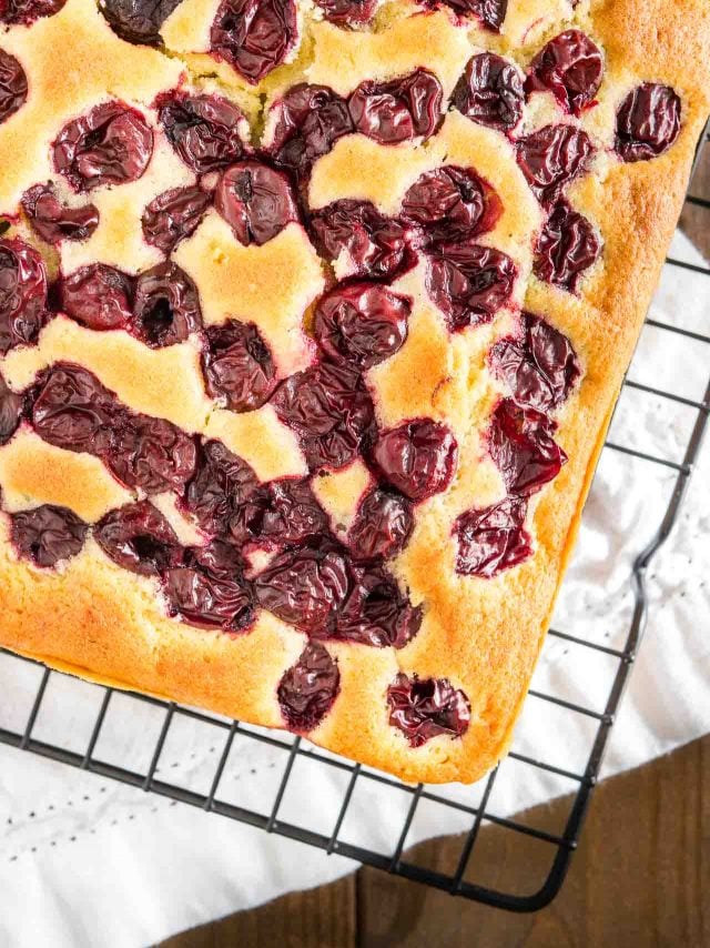 top-down shot of a cherry cake on a black cooling rack.