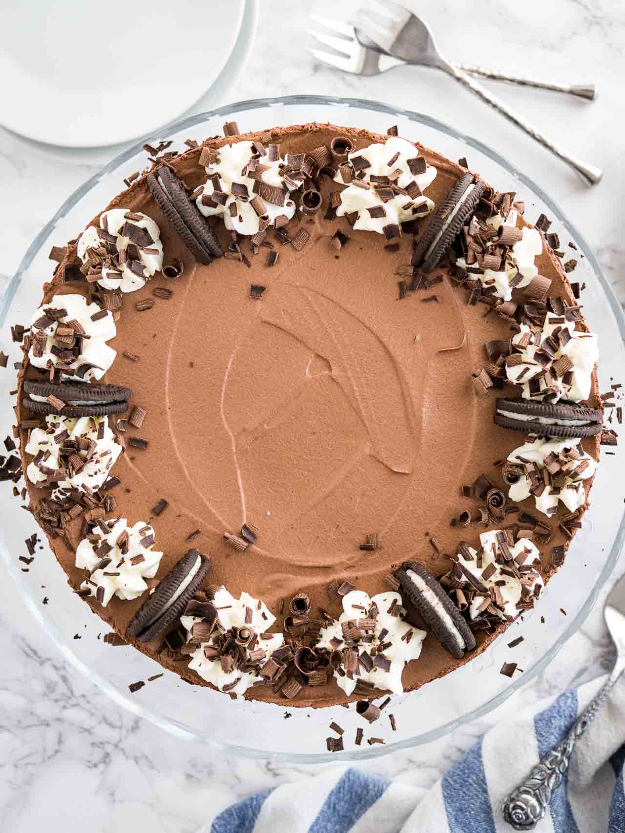 A no-bake mousse cake garnished with Oreo cookies, whipped cream, and chocolate curls.