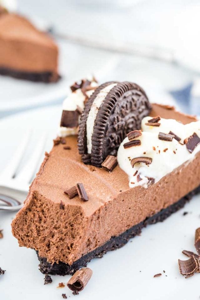 A slice of chocolate mousse cake on a marble surface with a fork next to it.