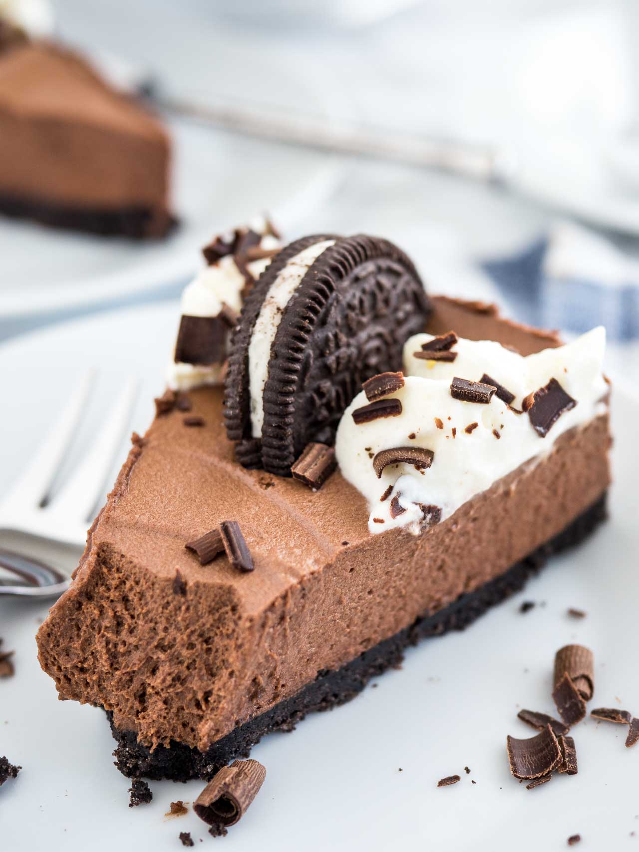 A slice of chocolate mousse cake on a marble surface with a fork next to it.