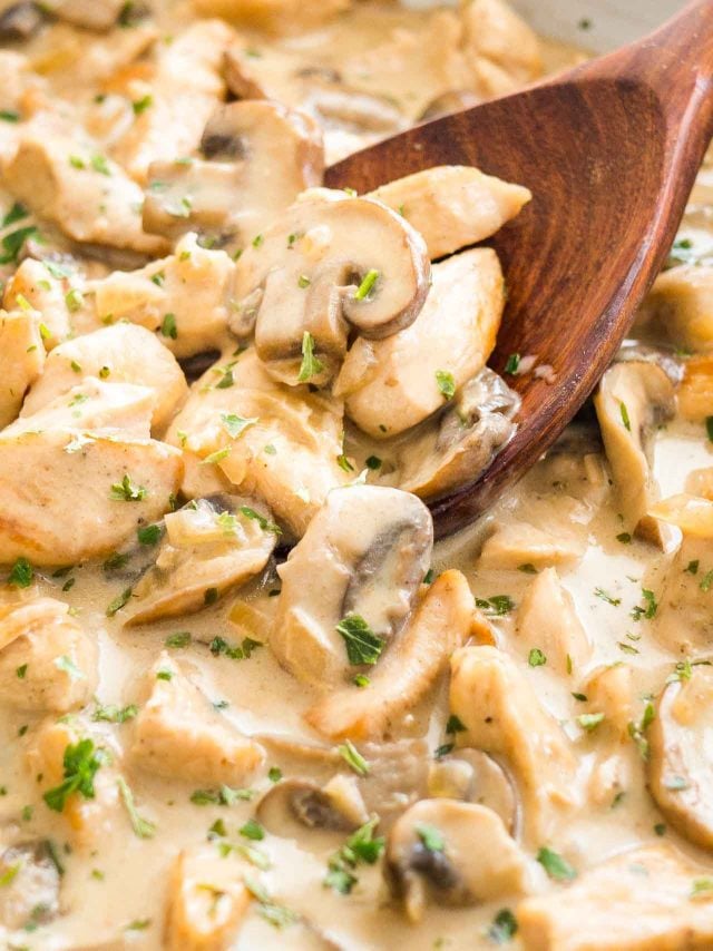 Close-up of Mushroom Chicken Pasta sauce with cream with a wooden cooking spoon in it.