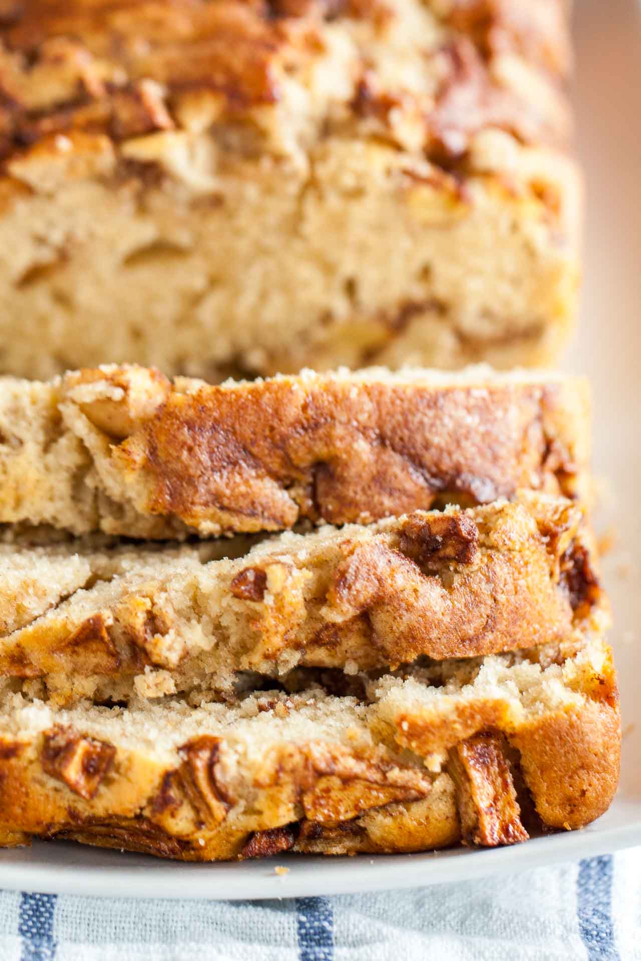 A loaf of apple cinnamon bread with slices cut off and lying in front of it.