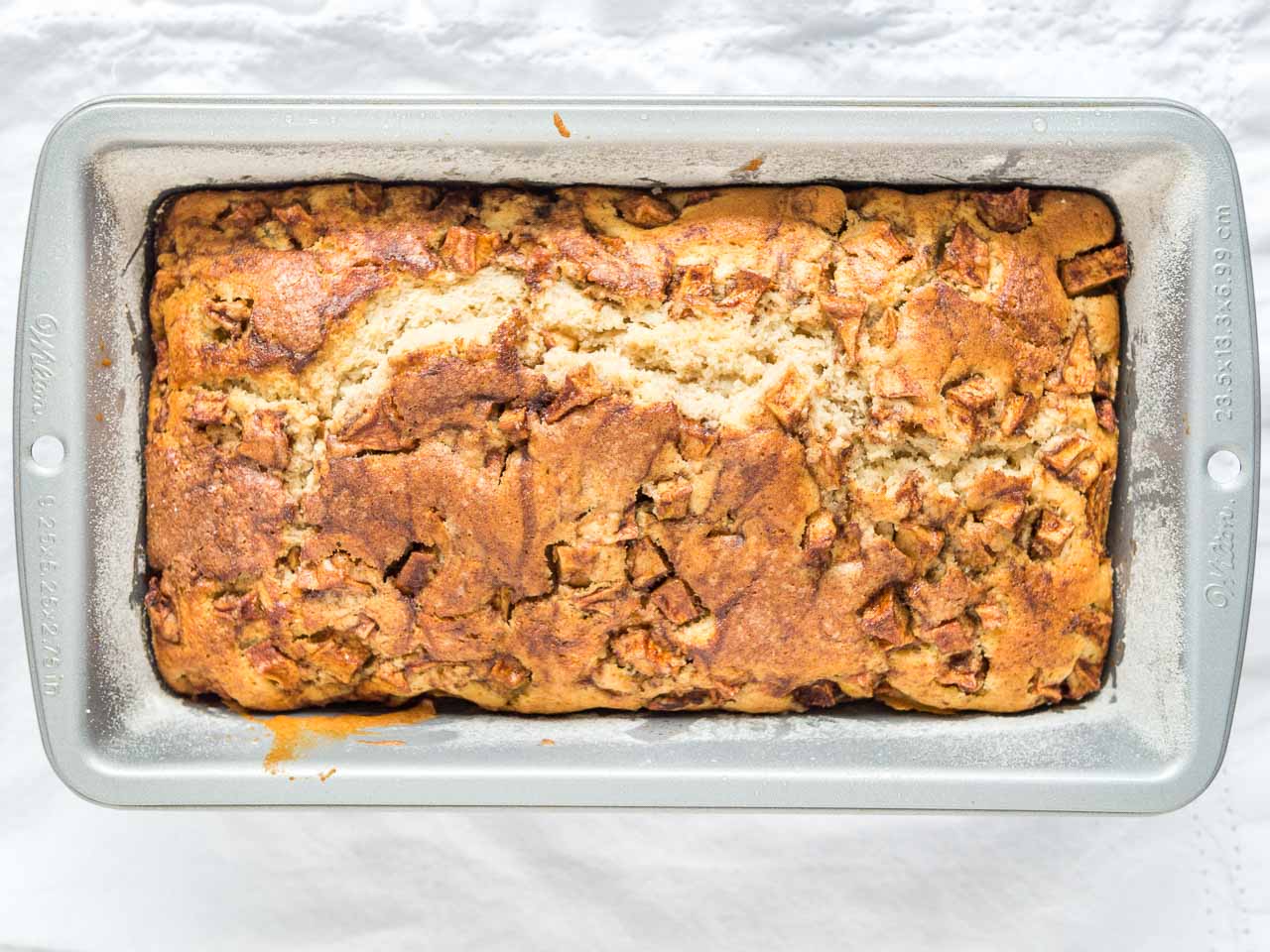 A floured bread pan with baked apple cinnamon bread.