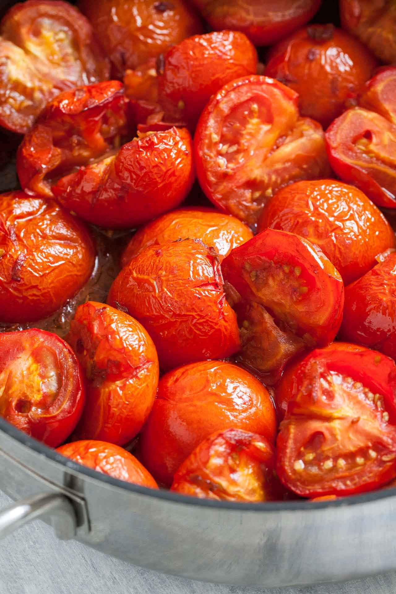 Roasted tomatoes with wrinkly skin in a large pan.