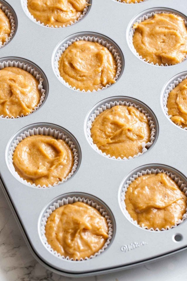 A muffin pan with liners and pumpkin spice batter.