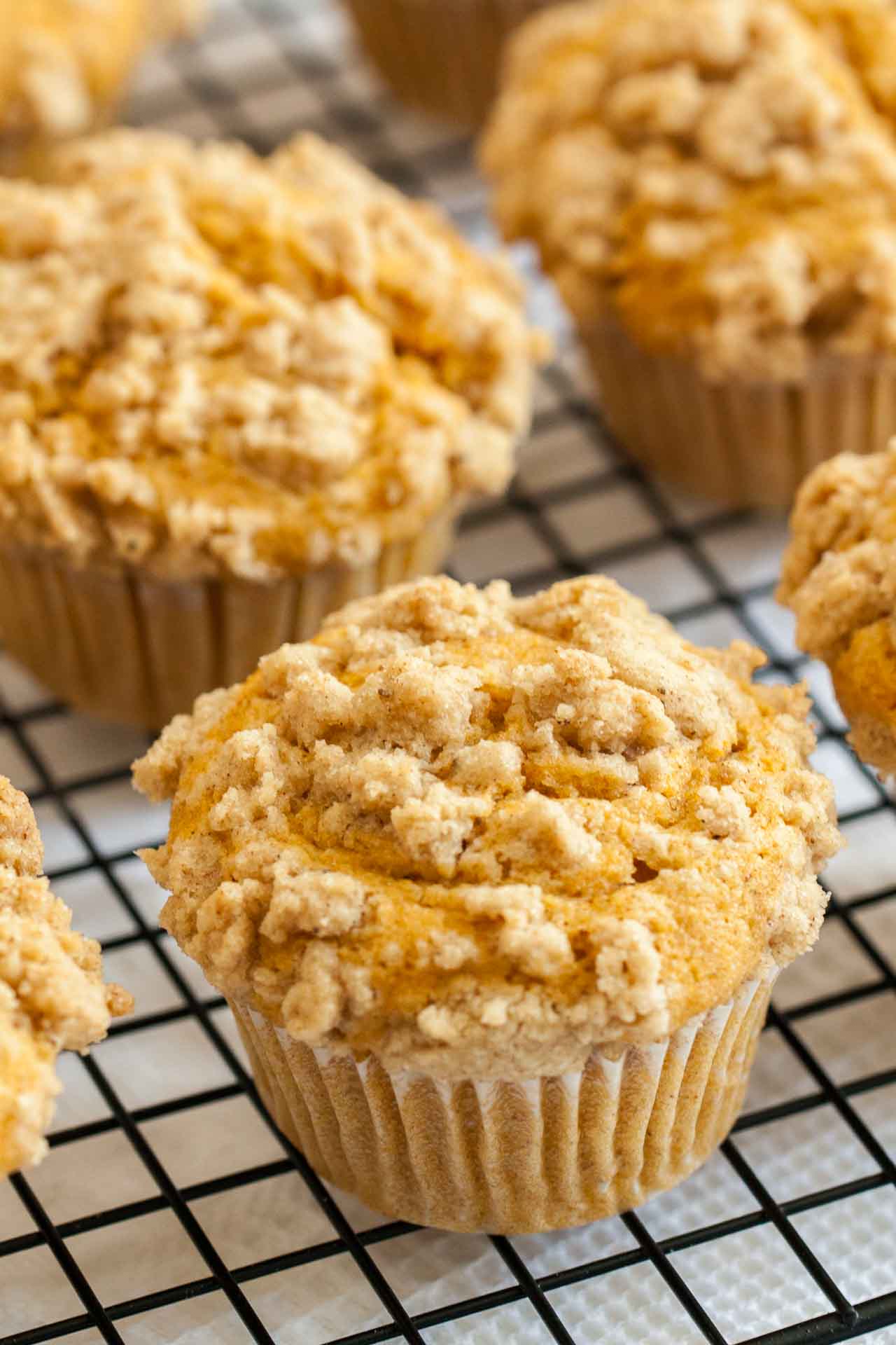Pumpkin spice muffins topped with streusel on a black cooling rack.