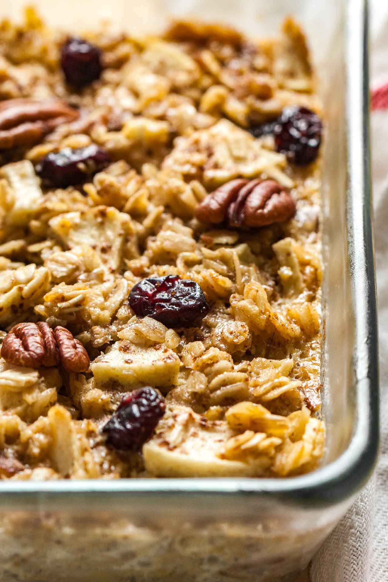 Close-up of a glass baking dish with baked oatmeal with apples, pecans and cranberries.