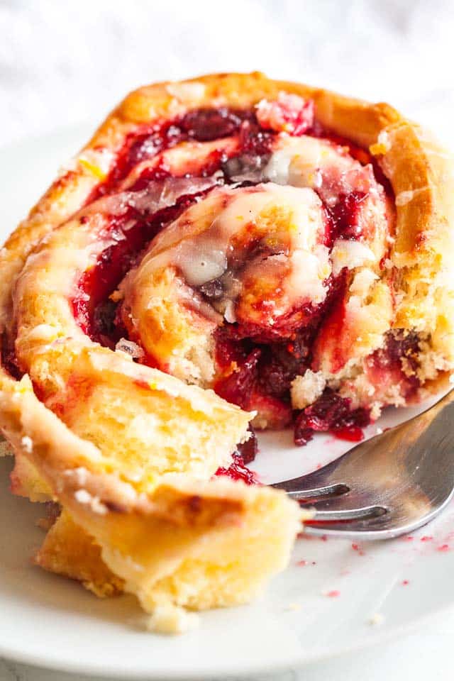 Close-up of a cranberry orange roll with a fork. The fork has taken out a piece of the roll.