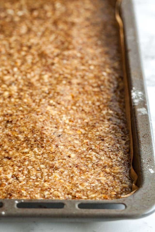 A baking pan, lined with parchment paper, with caramelized nut topping.