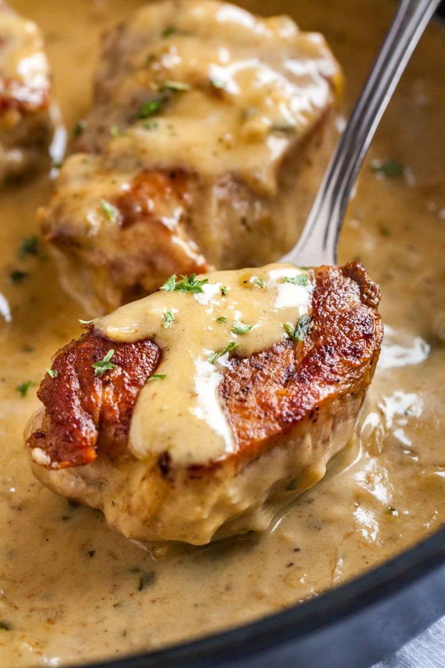 Close-up of a  seared pork medallion with a bit of blue cheese sauce on a spoon.