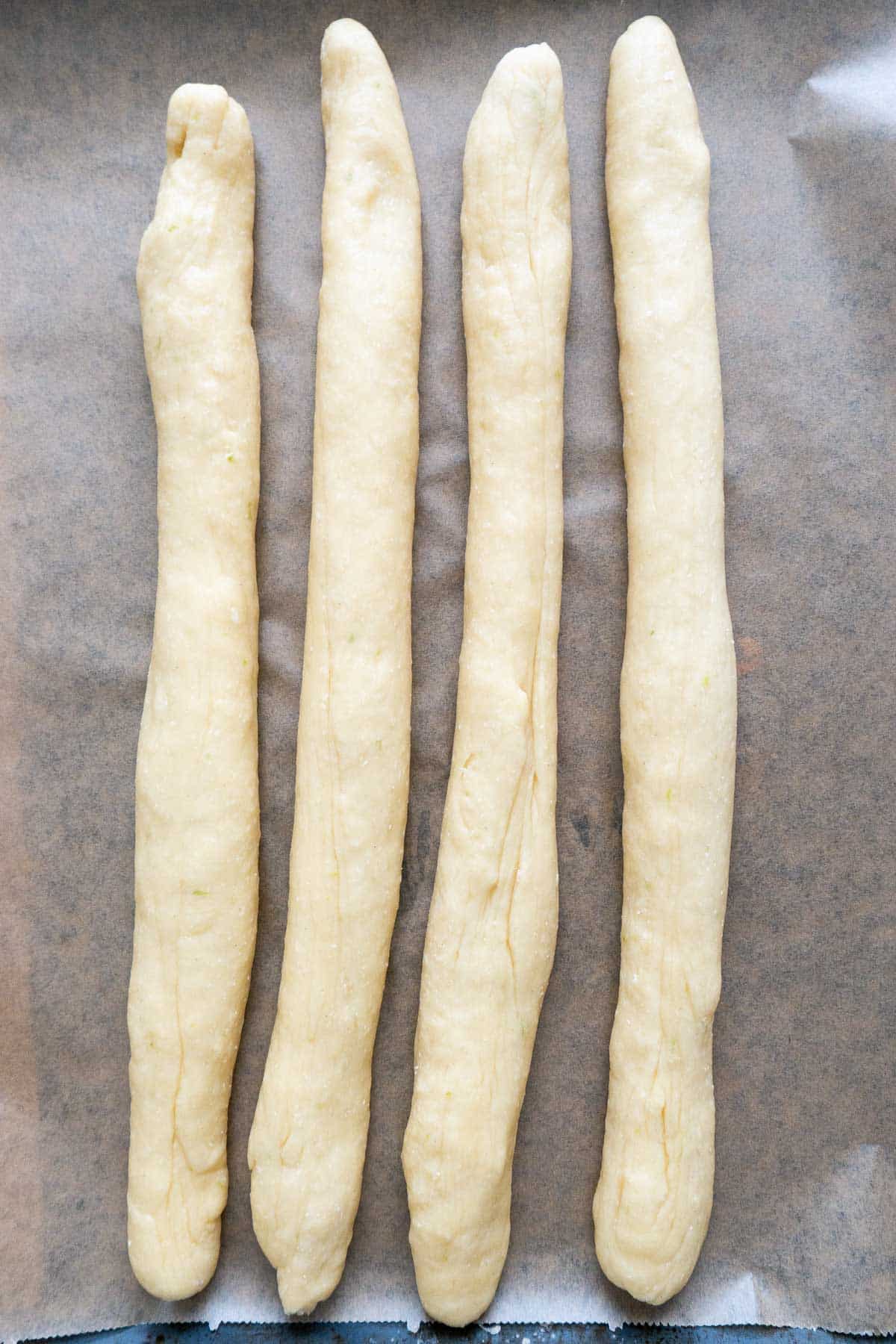 Four strands of dough on parchment.