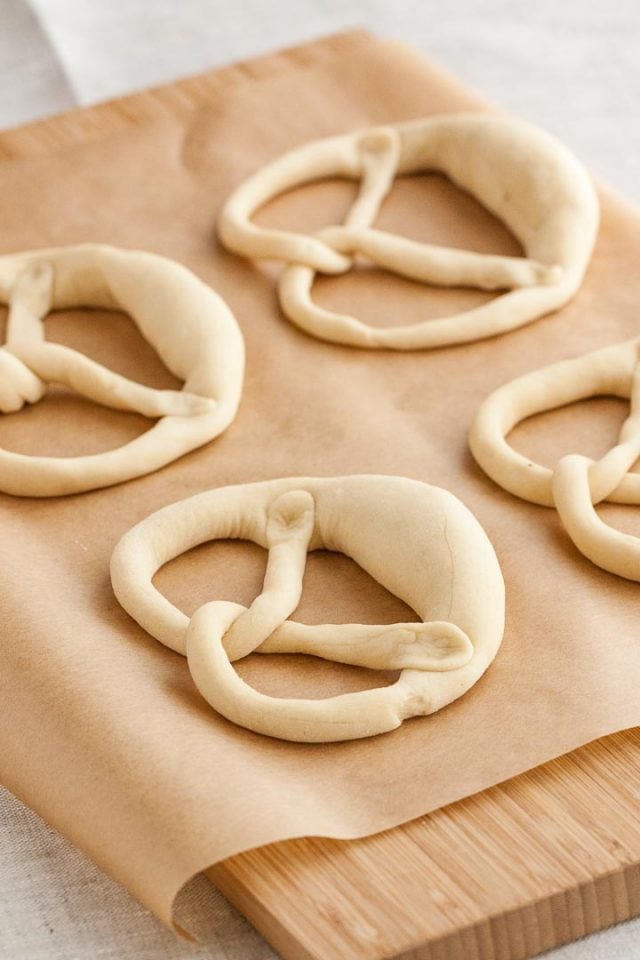 Four pretzels on parchment paper before baking.