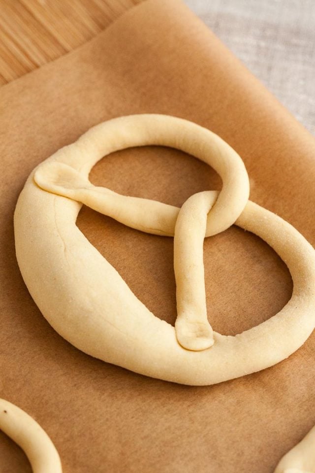 Pretzel dough, after being twisted, is folded over, to press both ends of the sausage into the thick part of the dough, making the pretzel shape.