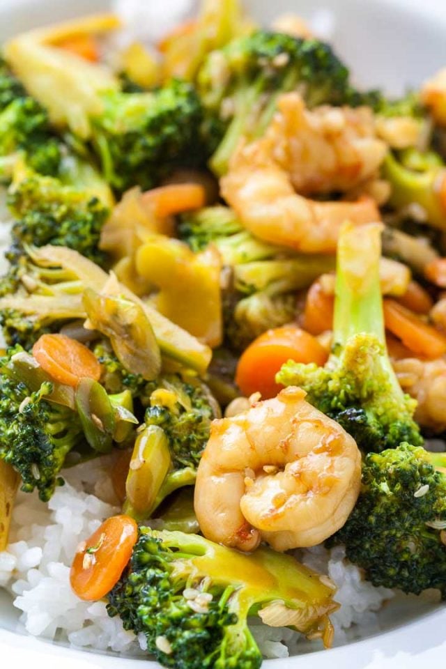 Close-up of a plate of rice topped with shrimp and broccoli stir fry.