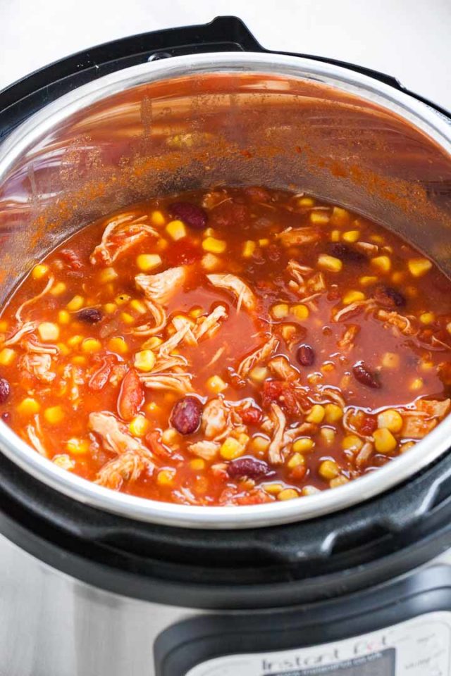 An instant pot with chicken chili containing shredded chicken, pinto beans and corn.