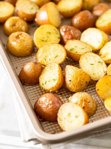 A baking sheet with roasted potatoes, garnished with parsley.