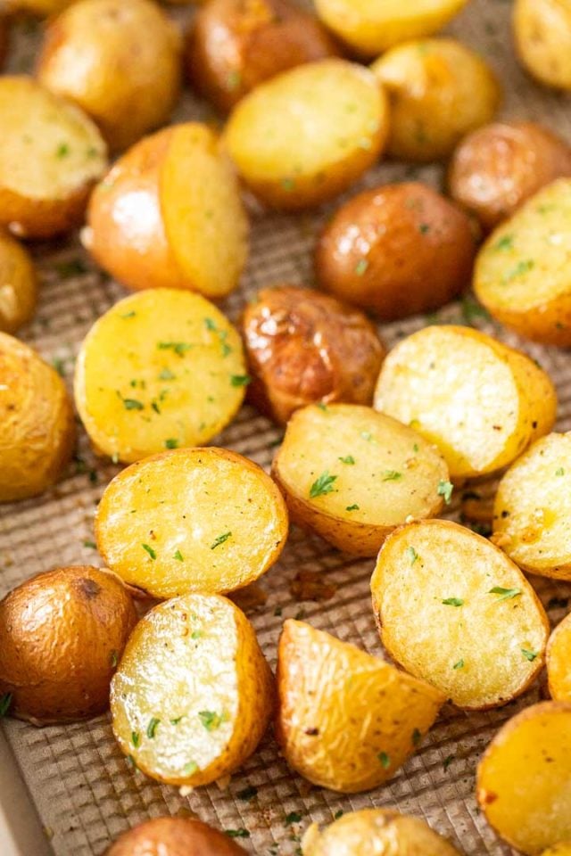 Close-up of a baking sheet with roasted potatoes, garnished with parsley.
