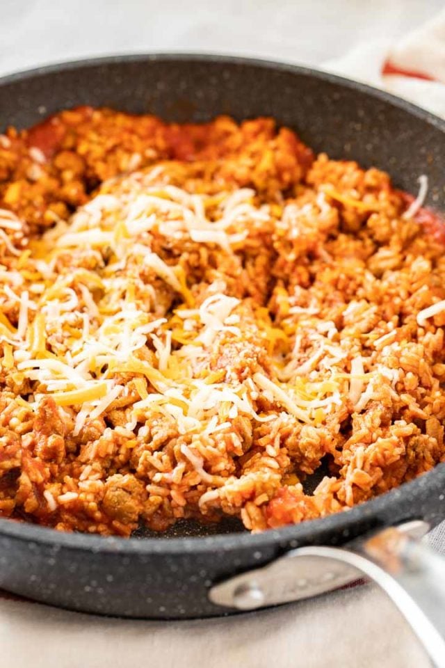 A grey rock pan with ground turkey stuffing topped with shredded cheese.