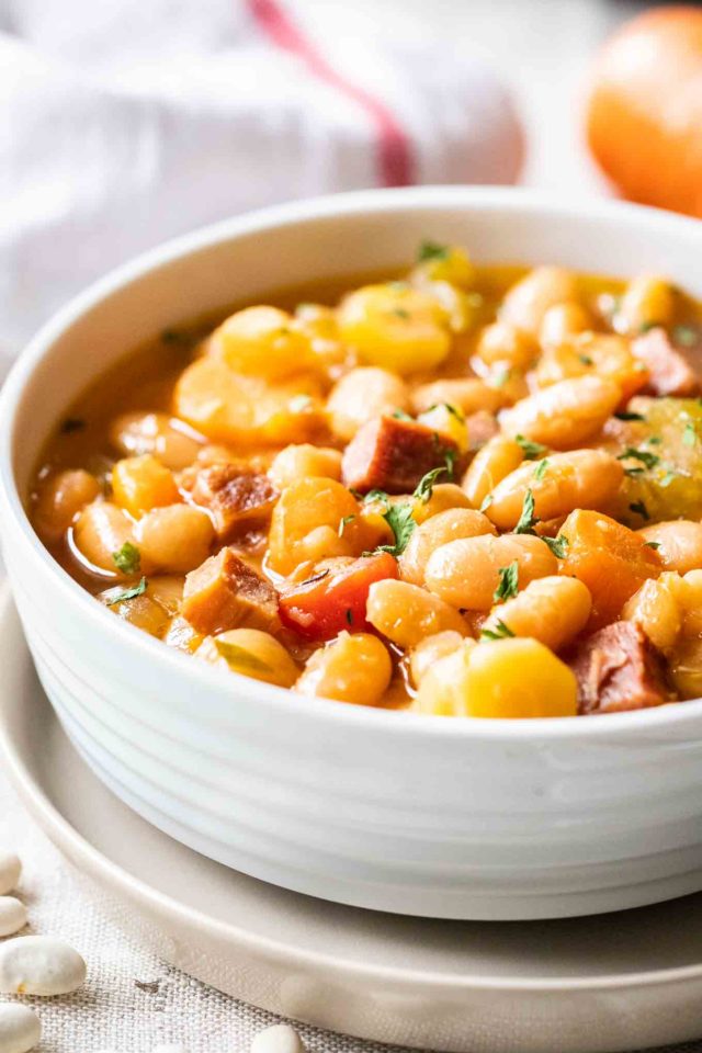 A white bowl containing ham and white bean soup, garnished with parsley.