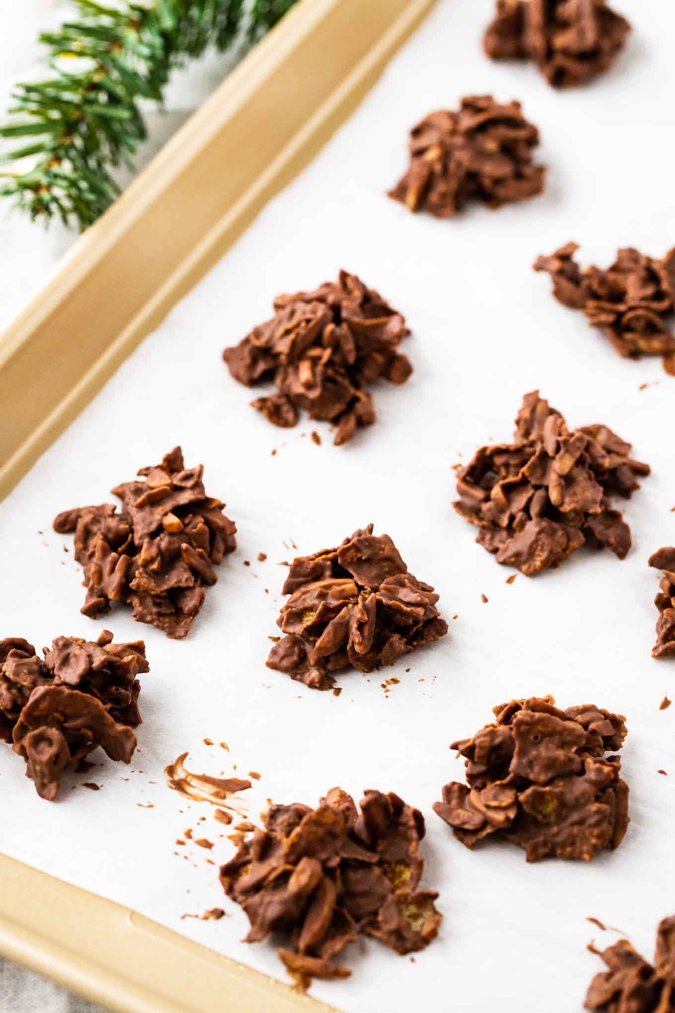 Cornflake Cookies are crunchy, chocolatey and so easy to make! You only need about 20 minutes to make a batch of these no-bakeย cookies that are a favorite in our house all year round but especially during the Holiday season. They make a delicious movie snack but would also be a perfect edible gift! #cornflakecookies #NoBakeCookies #ChocolateNoBakeCookies Cornflake cookies on a baking sheet.