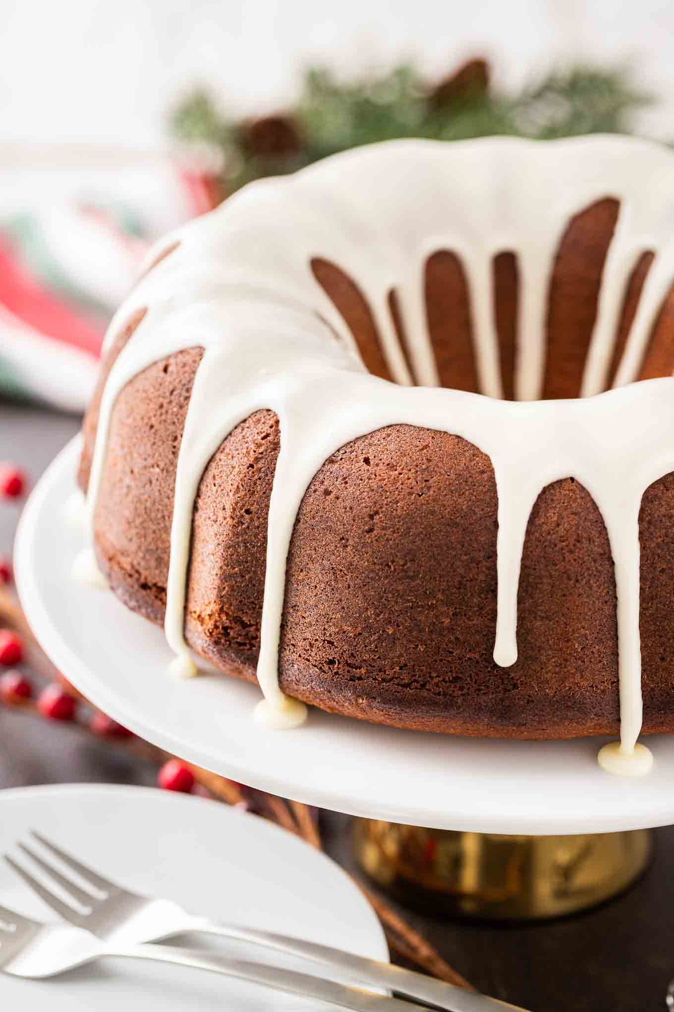 A bundt cake with white glaze dripping off it on a white platter.