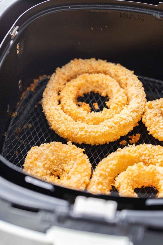 A single layer of onion rings in an air fryer basket